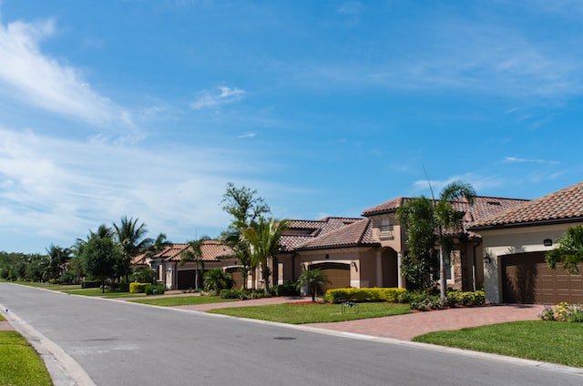 three homes on a neighborhood street with palm trees